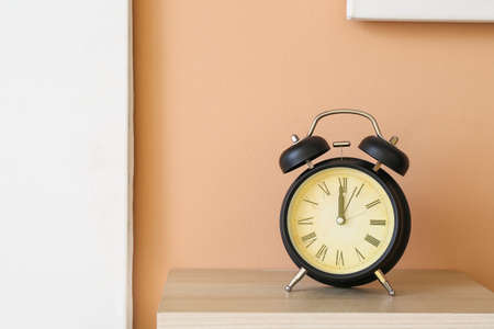 Alarm clock on shelf near color wallの写真素材