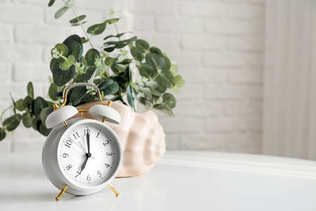 Alarm clock with floral decor on table in roomの写真素材