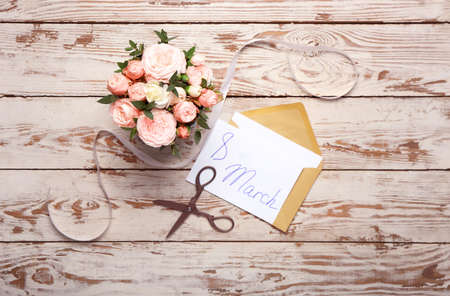 Beautiful flowers and greeting card for International Women's Day on white wooden background