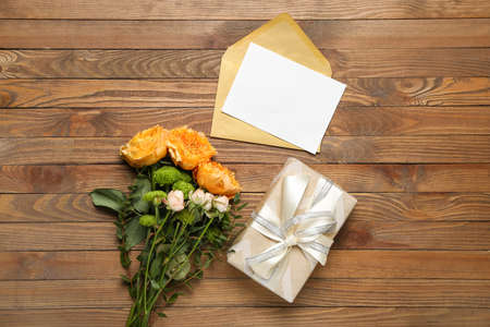 Bouquet of beautiful flowers, gift and blank card on wooden backgroundの写真素材