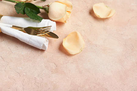 Cutlery and rose flowers on color background. Valentines Day celebration