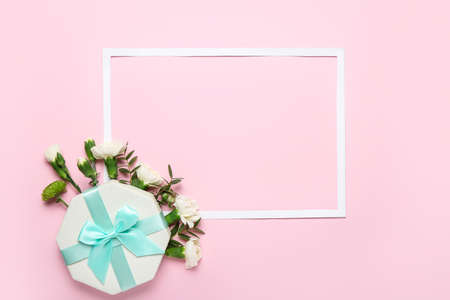 Frame with beautiful flowers and gift on color backgroundの写真素材