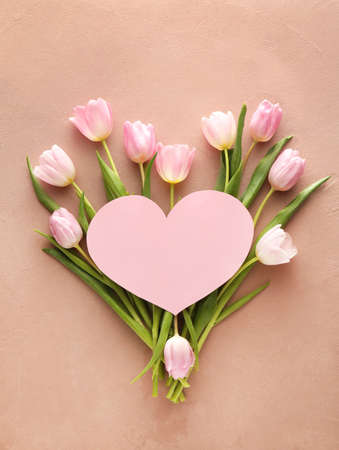 Blank heart-shaped card and beautiful flowers on color backgroundの写真素材