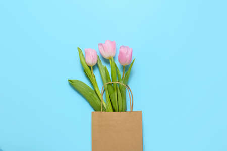 Paper bag with beautiful tulip flowers on color backgroundの写真素材