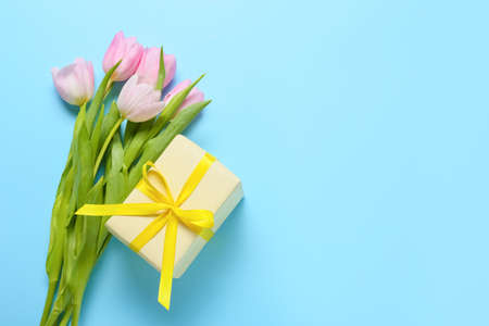 Beautiful flowers and gift on color backgroundの写真素材