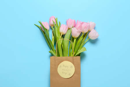 Beautiful flowers and greeting card for International Women's Day on color background
