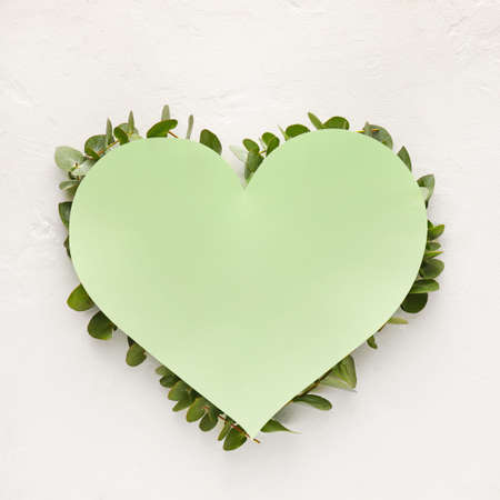 Blank heart-shaped card and green branches on light backgroundの写真素材