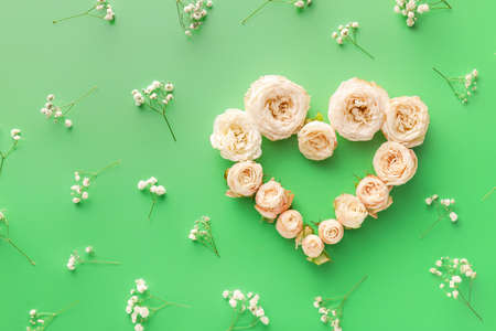 Heart made of beautiful flowers on color background