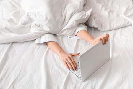 Young woman using laptop in bedroomの写真素材