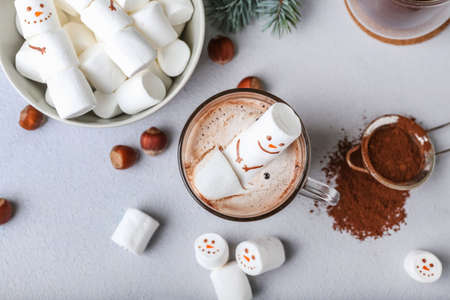 Snowman made of soft marshmallows and cup of hot chocolate on light backgroundの写真素材