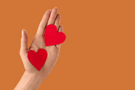 Hand with red hearts on color background