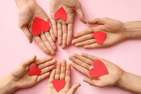 Hands with red hearts on color backgroundの写真素材