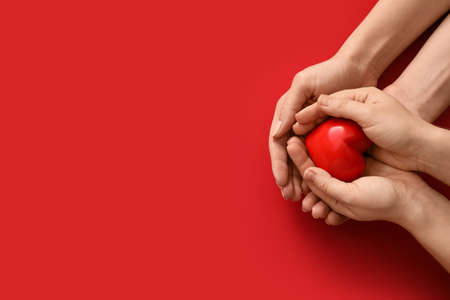 Hands with red heart on color backgroundの写真素材