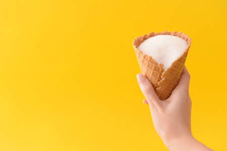 Woman holding waffle cone with sugar on color backgroundの写真素材