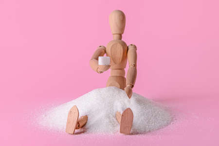 Wooden mannequin with sugar on color backgroundの写真素材
