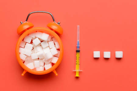 Alarm clock with sugar and syringe on color background