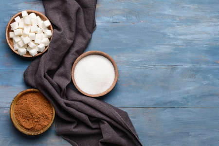 Bowls with sugar on color wooden background