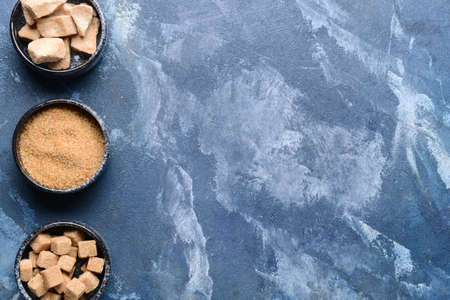 Bowls with sugar on color background