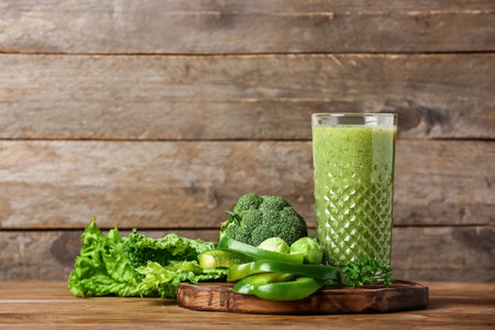 Glass of healthy green smoothie and vegetables on wooden backgroundの写真素材