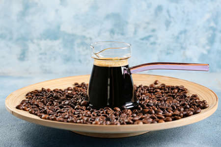 Pot with delicious turkish coffee and plate with beans on color backgroundの写真素材