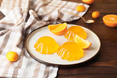 Plate with tasty orange jelly on dark wooden backgroundの写真素材