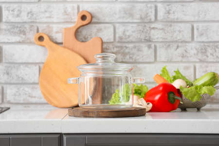 Stylish cooking pot and fresh vegetables on table in kitchenの写真素材