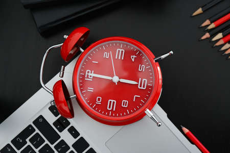 Alarm clock and laptop on dark background, closeupの写真素材