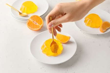 Woman eating tasty orange jelly on white background, closeupの写真素材