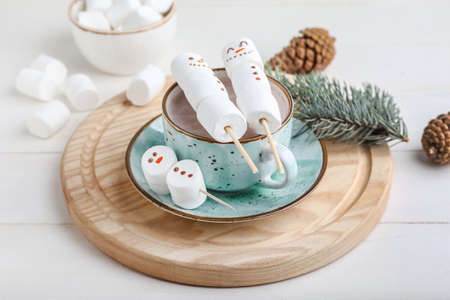 Snowmen made of soft marshmallows and cup of hot chocolate on tableの写真素材