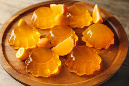 Plate with tasty orange jelly on wooden background, closeupの写真素材
