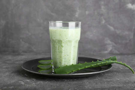 Tray with glass of healthy aloe juice on grunge backgroundの写真素材