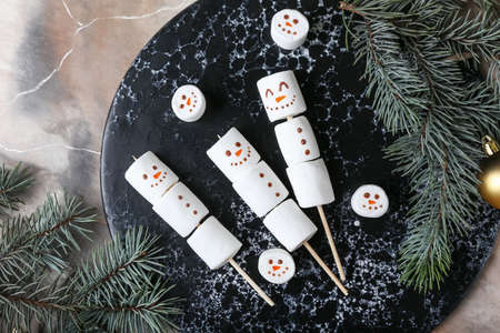 Board with snowmen made of soft marshmallows on grunge backgroundの写真素材