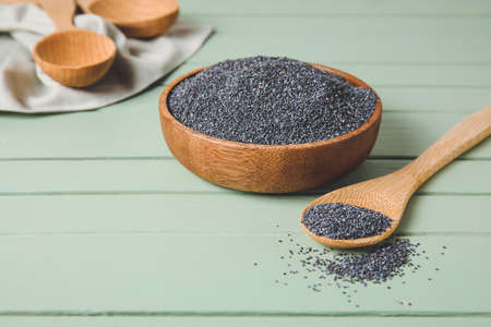 Bowl and spoon with poppy seeds on color wooden backgroundの写真素材