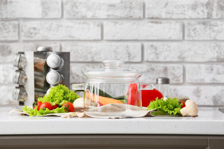 Stylish cooking pot and fresh vegetables on counter in kitchenの写真素材