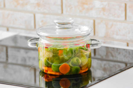 Stylish cooking pot with vegetables on stove in kitchenの写真素材