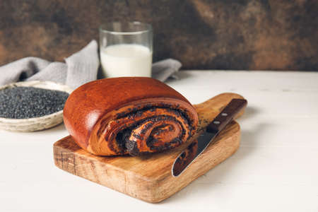 Tasty bun with poppy seeds on light wooden backgroundの写真素材