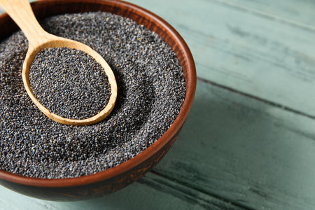 Bowl and spoon with poppy seeds on color wooden backgroundの写真素材