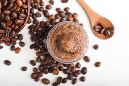 Jar with body scrub and coffee beans on light backgroundの写真素材