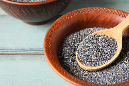 Bowl and spoon with poppy seeds on color wooden backgroundの写真素材