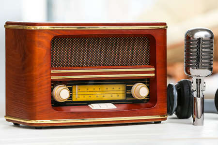 Retro radio receiver with microphone and headphones on table in roomの写真素材
