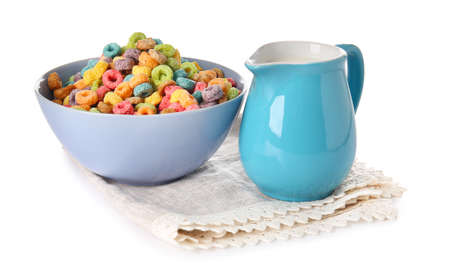 Bowl with cereals and jug of milk on white background