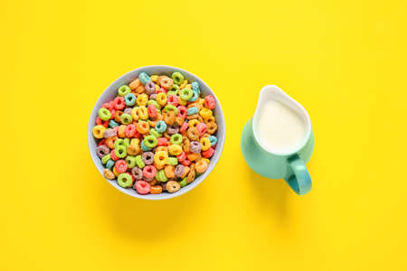 Bowl with cereals and jug of milk on color background
