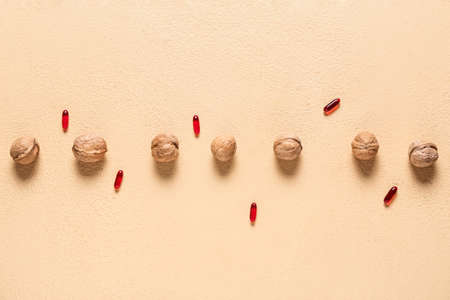 Walnuts with pills on color background