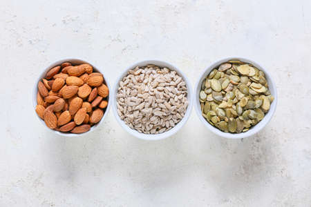 Bowls with sunflower, pumpkin seeds and almond nuts on grunge backgroundの写真素材