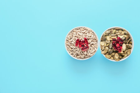 Bowls with pumpkin, sunflower seeds with pills on color background