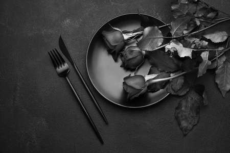 Beautiful rose and table setting on dark background