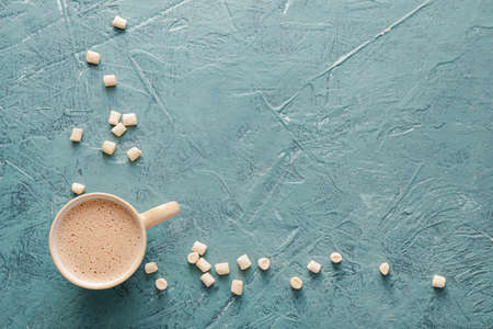 Composition with cup of hot cocoa drink and marshmallows on color background