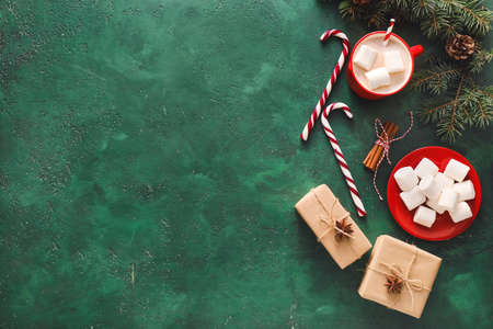 Cup of hot cocoa drink, fir branches and gift boxes on color backgroundの写真素材