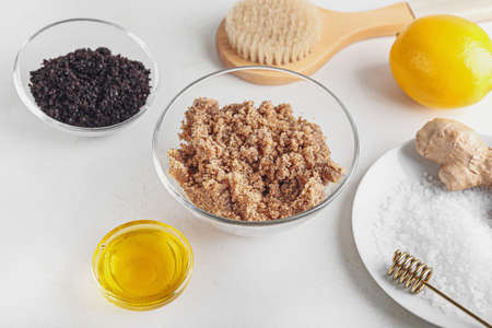 Bowl with natural scrub, ingredients and massage brush on white backgroundの写真素材