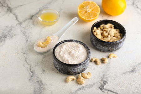 Bowls with cashew sour cream, nuts and lemon juice on light backgroundの写真素材